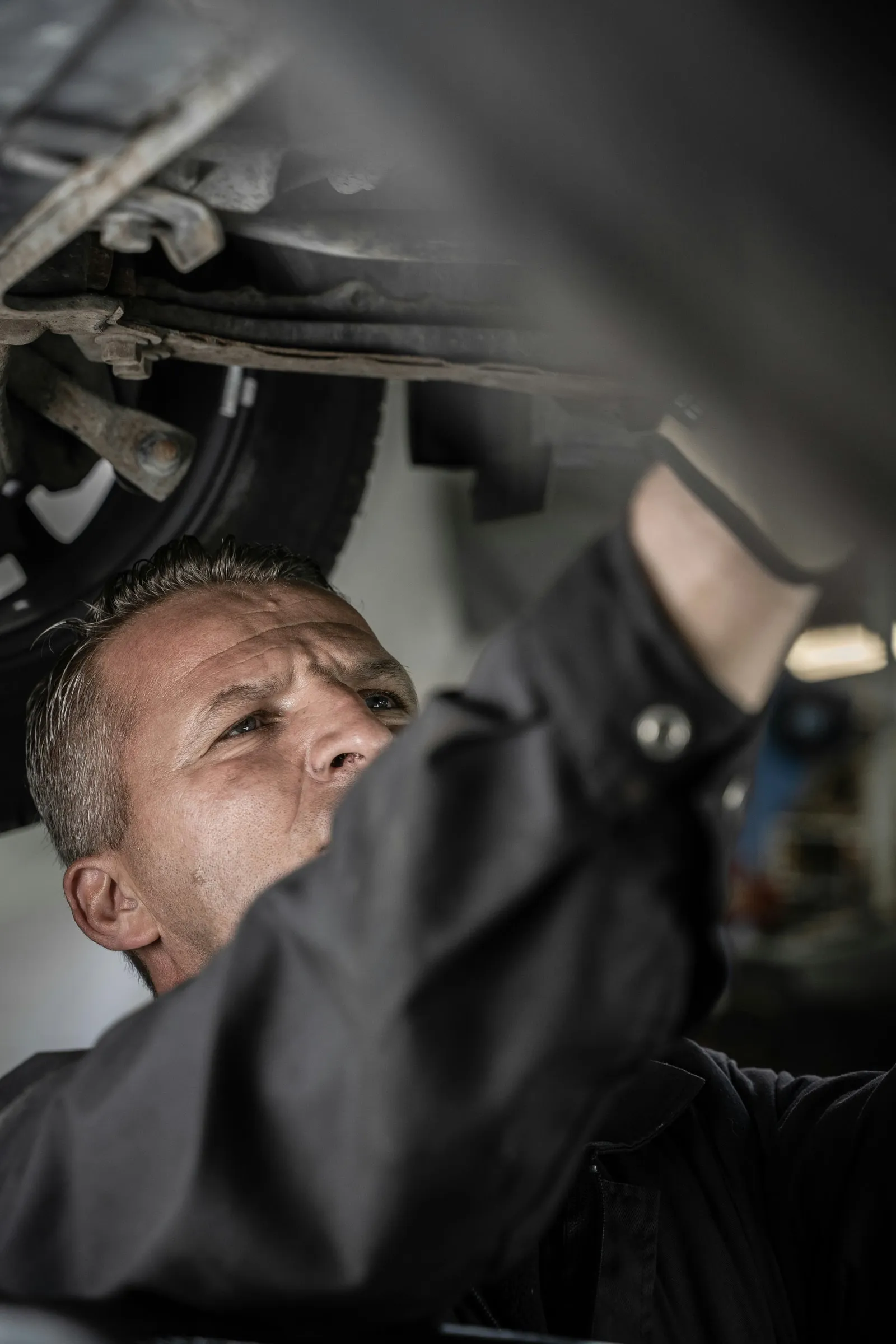 Sfeerbeeld: een mecanicien werkt onder een wagen op de brug